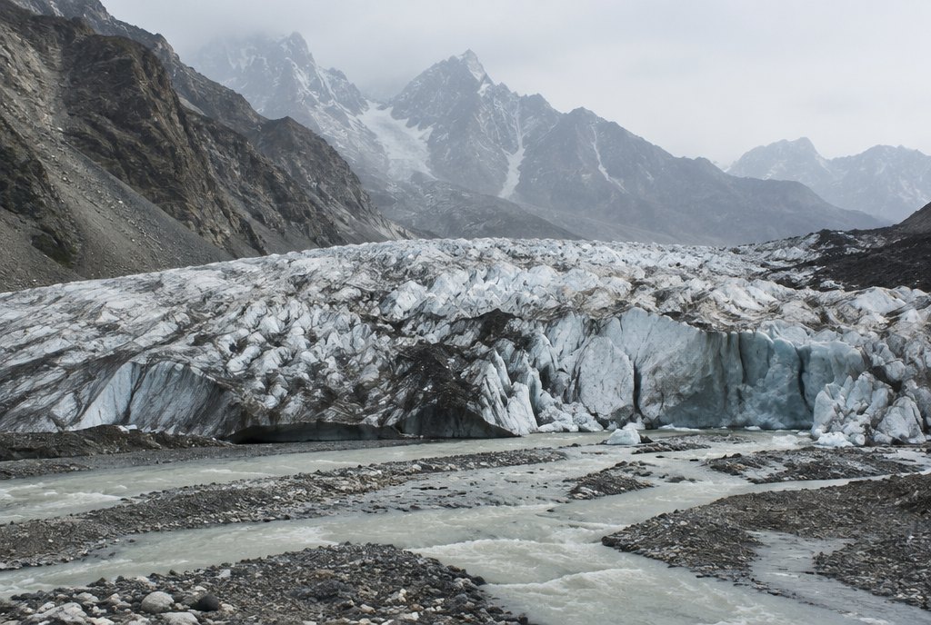 Karakoram glacier tongue with meltwater streams under a hazy sky